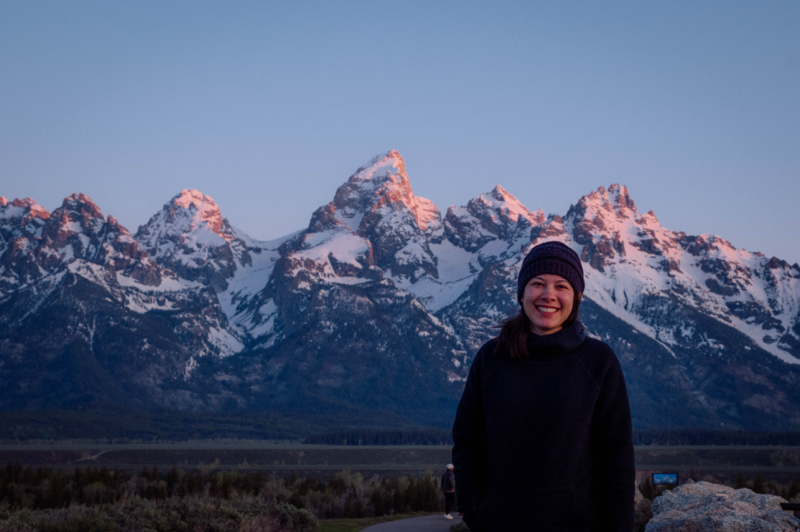 Girl smiling with snow covered Teton range in the background.