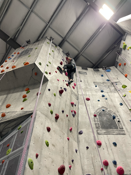 Smiling girl at the top of a climbing route at a climbing gym